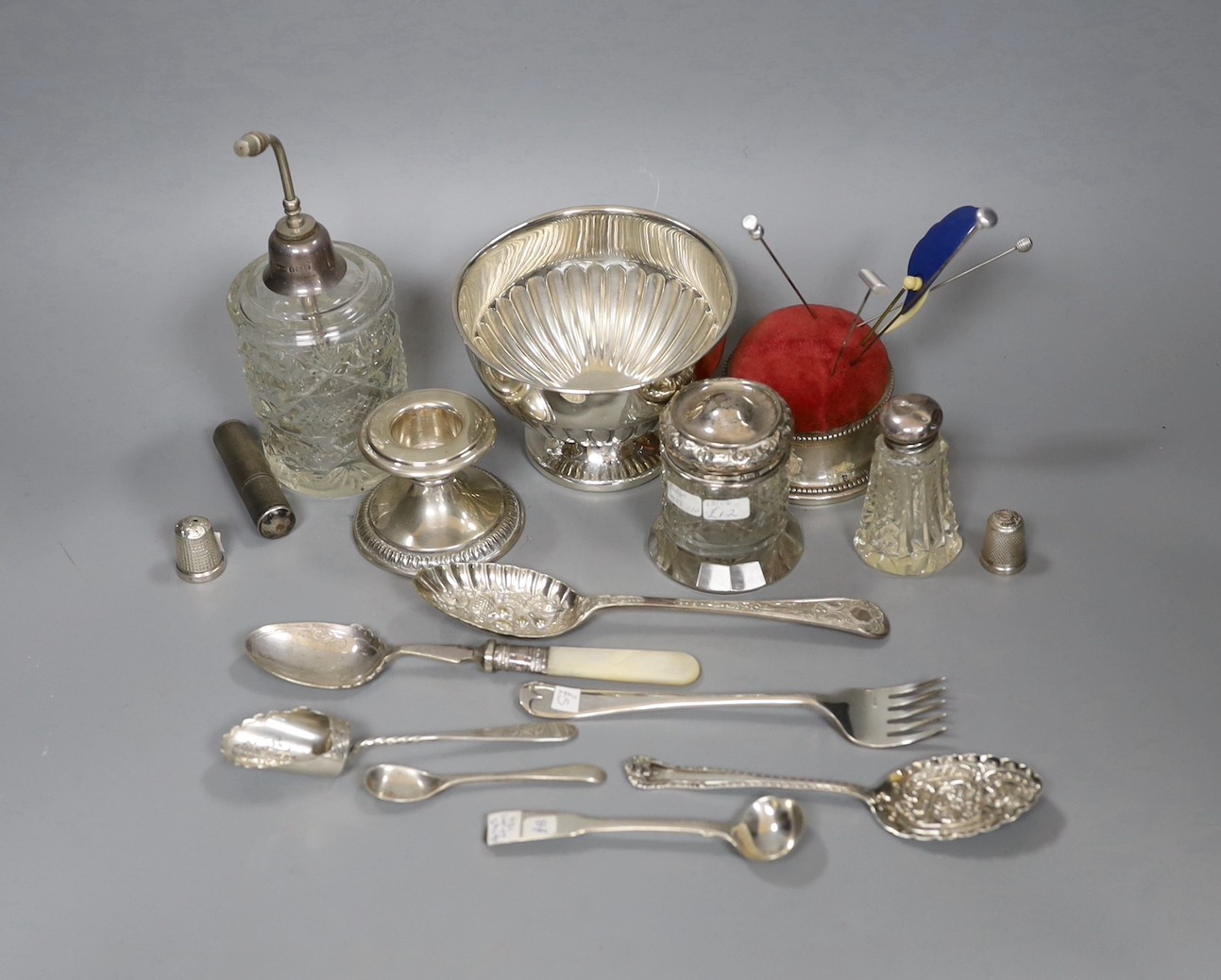 Small silver items including 800 standard dwarf candlestick, a George V silver mounted pin cushion, a silver mounted glass atomiser and two toilet jars, a sterling lighter, two silver thimbles, four items of silver flatw